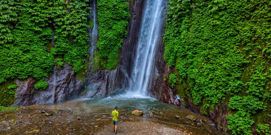 Man standing at the foot of the Red Coral waterfall in Munduk, Bali