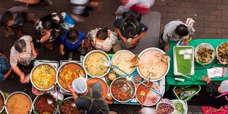 People buying food at a street food market in Thailand