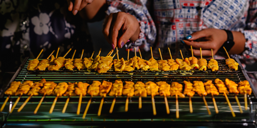 Women cooking moo satay on the grill