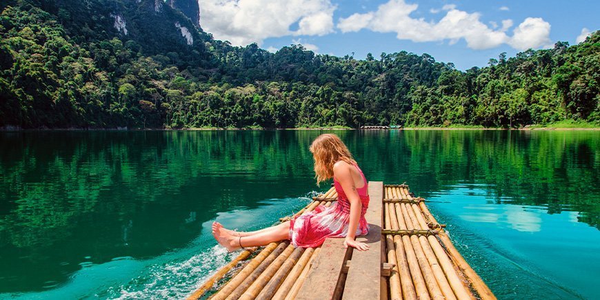 Young girl sitting by the lake in Khao Sok National Park in Thailand