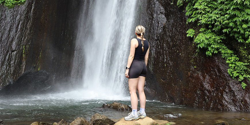 TourCompass member, Louisa, standing in front of the Red Coral Waterfall in Bali