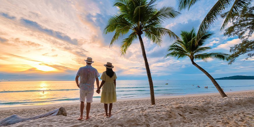 Couple holding hands and watching the sunset on Phuket beach