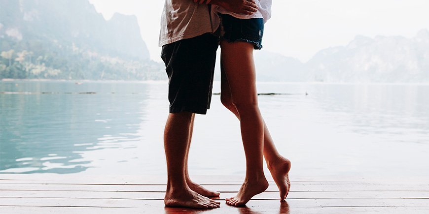 Couple standing close together on a bridge overlooking water