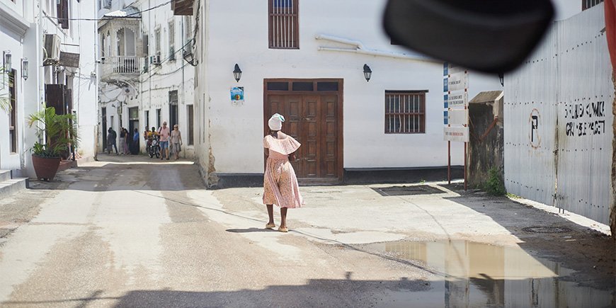 Woman in dress walks through the streets of Stone Town