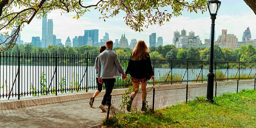 Couple walking hand in hand in sunny weather in Central Park, New York City